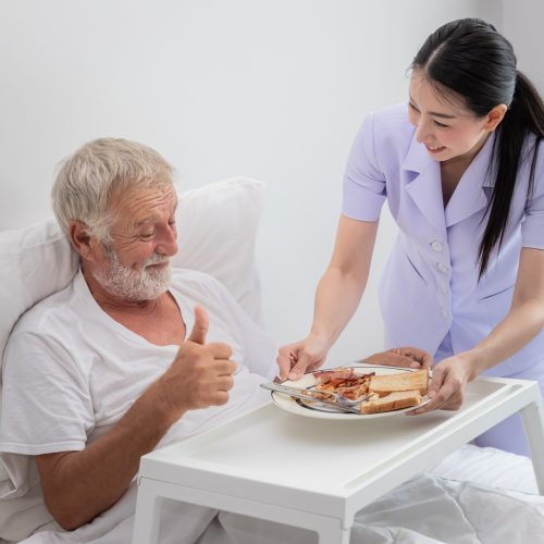 happy-nurse-serving-elderly-senior-man-breakfast-bed-bedroom-nursing-home-thumb-up